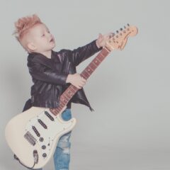 boy wearing black jacket holding electric guitar