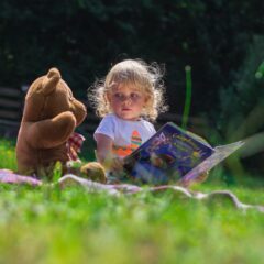 girl sitting beside a teddy bear